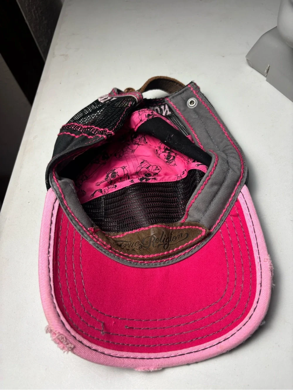 pink, distressed True Religion brand jeans cap with embroidered wings and a logo